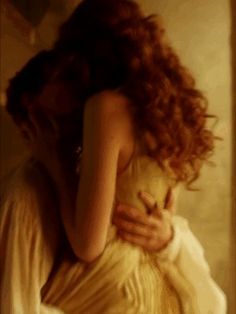 a woman with red hair is hugging another woman's back in a white dress