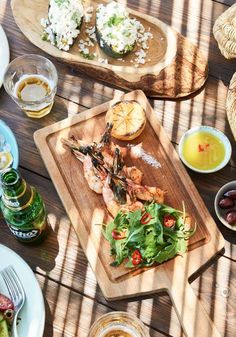 a wooden table topped with plates and bowls filled with different types of food on top of it