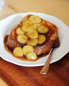 french toast topped with bananas and syrup on a white plate