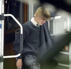 a young man wearing a sweater and tie on a train