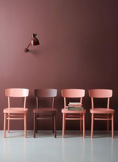 four chairs are lined up in front of a wall with a clock on the side