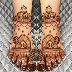 two feet with henna tattoos on them, one is showing it's intricate designs