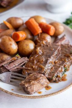 a white plate topped with meat, potatoes and carrots