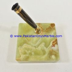 a pen sitting on top of a green marble block with gold and black trimmings