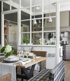 a dining room table set with place settings and chairs, in front of the kitchen