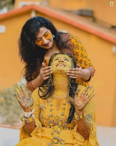 a woman with her face painted in yellow and holding onto another woman's head