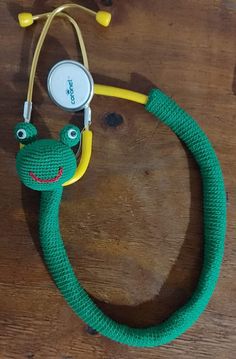 a green snake with a stethoscope attached to it's neck on a wooden table