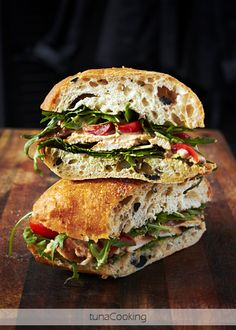 a sandwich cut in half sitting on top of a wooden cutting board