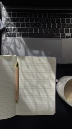 an open notebook sitting on top of a desk next to a laptop computer