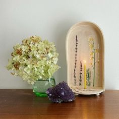 a vase filled with flowers sitting next to a candle holder on a wooden table top