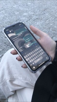 a person holding an open cell phone in their hand on the street with cobblestone pavement