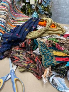 a pile of scarves sitting on top of a table next to a pair of scissors