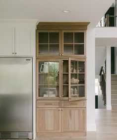 an empty kitchen with wooden cabinets and stainless steel refrigerator in the center, on hard wood flooring