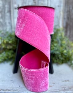 a pink ribbon sitting on top of a wooden table next to a potted plant