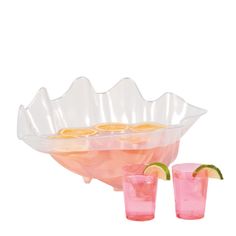 two glasses filled with pink lemonade and limes next to a large serving bowl