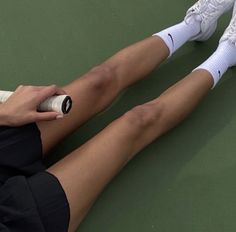 a tennis player is sitting on the court with her foot in the air