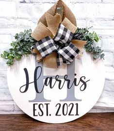 a wooden sign that says harris est 2021 hanging on a brick wall with greenery