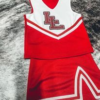 a red and white cheer uniform laying on top of a bed