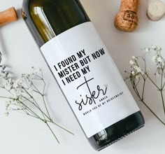 a bottle of wine sitting on top of a table next to flowers and corks