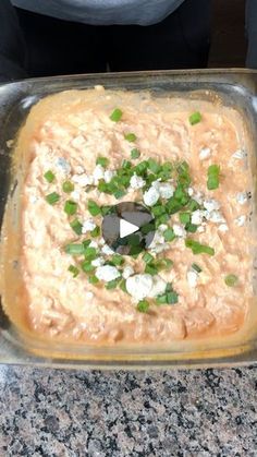 a casserole dish with green onions and feta cheese in it on a granite countertop