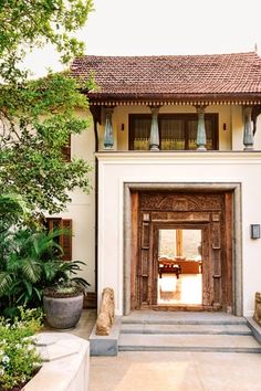 an entrance to a house with plants and potted trees