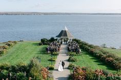 a bride and groom are walking down the aisle to their wedding ceremony by the water