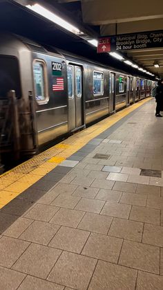 a subway train pulling into the station with people walking on the platform next to it