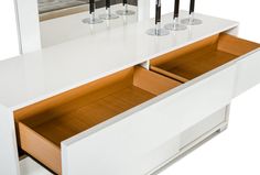 two wine glasses are sitting in the bottom drawer of a white counter with drawers underneath