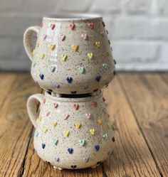 two ceramic cups with hearts on them sitting on a wooden table