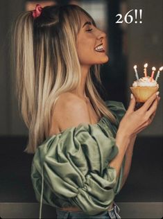 a woman holding a cupcake with candles in it and the words happy birthday to you