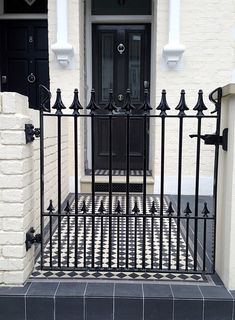 a black iron gate is in front of a white brick building with a black door