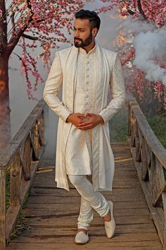 a man standing on a bridge in white clothes