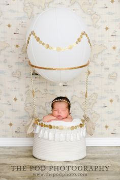 a baby is laying in a basket with a balloon attached to the top of it