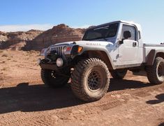 a white jeep is parked in the desert