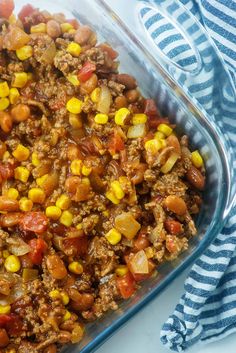 a glass casserole dish filled with ground beef and corn, on top of a striped towel