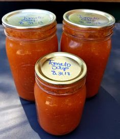 three jars filled with tomato sauce sitting on top of a blue cloth covered tablecloth