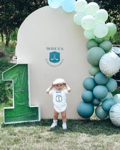 a little boy standing in front of a giant balloon arch