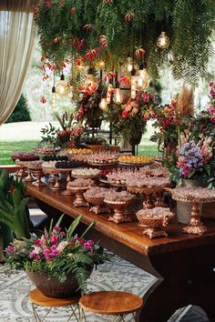 a long table covered in lots of food and flowers on it's side with lights hanging from the ceiling