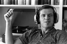 a man wearing headphones sitting in front of a book shelf with books on it