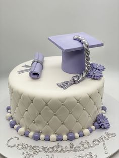 a white cake with purple decorations and a graduation cap on top