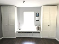 an empty room with some white cabinets and drawers on the wall next to a window