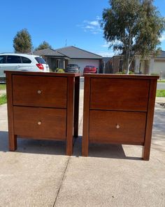 two wooden dressers side by side in front of a house with cars parked on the driveway