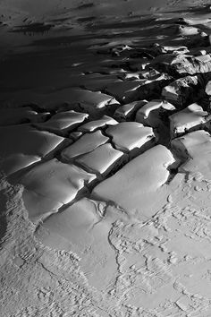 an aerial view of snow and ice on the ocean floor, taken in black and white