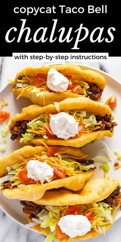 three tacos with cheese, lettuce and tomato on them sitting on a white plate