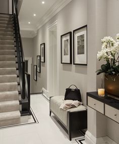 a white and black hallway with flowers on the bench, pictures hanging on the wall