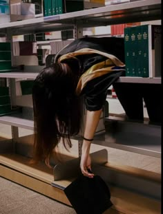 a woman bending over on top of a book shelf