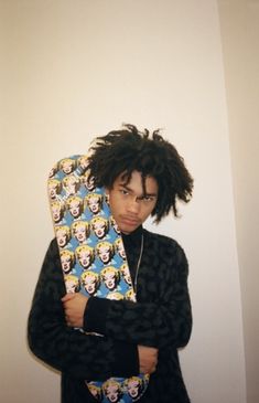 a man with dreadlocks holding a skateboard in front of his face and looking at the camera