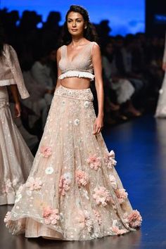 This gorgeous peach hued lehenga is a testament to heavenly aesthetics and whimsical hues. Flaunts of traditional craftsmanship with ultra-mod 3-d embroidery. Prettified with larger-than-life florals, this stunner comes with a sequin blouse. 
3-d florals
embellished detail
sequin blouse
sleeveless blouse
frill detail - Aza Fashions Embellished Lehenga, Lehnga Dress, Lehenga Skirt, Sequin Blouse, Lehenga Collection, Designer Baby, Lakme Fashion Week, Blouse Sleeveless, Indian Clothes