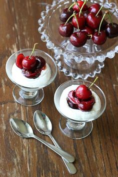 small desserts with cherries and whipped cream in glass dishes on a wooden table