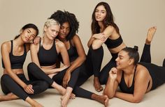 four women in black sports bra tops and leggings posing for a photo together